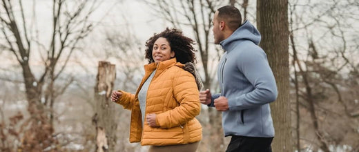 man and woman walking briskly in the cold near snow