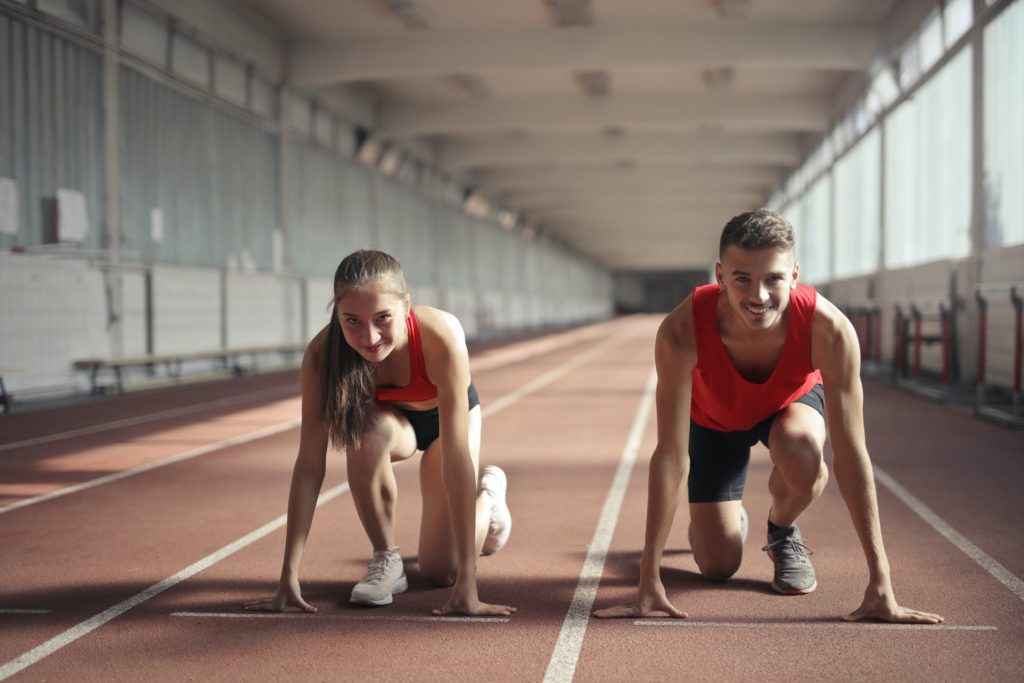 man and woman preparing to run a race on a track