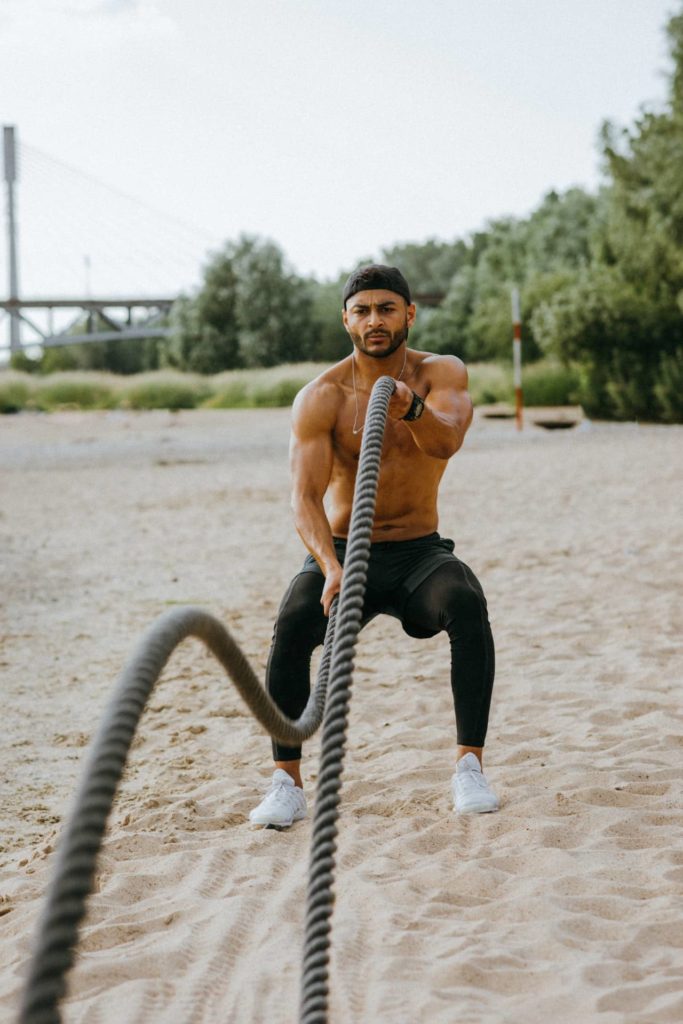 man working out with ropes on a beach