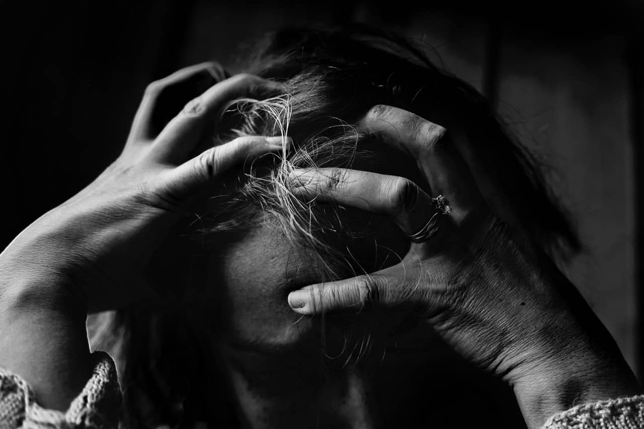 black and white image of a woman holding her head in stress
